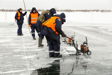 Workers cut ice blocks to the size of ice on a frozen lake