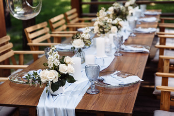 Festive table. The festive table is decorated with flowers, greenery, candles, a blue tablecloth, crystal plates, glasses