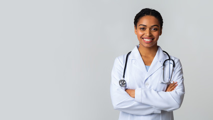 Smiling Black Female Doctor In White Coat Posing With Folded Arms - Powered by Adobe