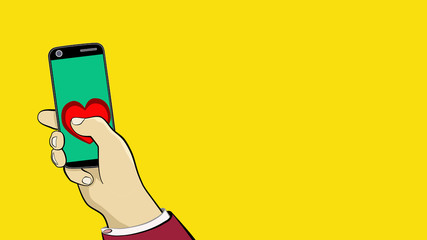 Hand of a man. Holds a smartphone with a green screen. Nearby is a bright red heart. Congratulations on Valentine's Day. You can replace the background.