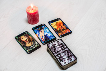Fototapeta na wymiar Color tarot cards with red candles on a white wooden table background. Concept of divination
