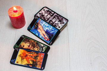 Color tarot cards with red candles on a white wooden table background. Concept of divination