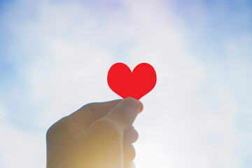 heart in hand on blue background of sky and clouds