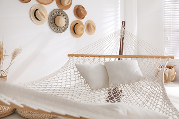 Fototapeta na wymiar Comfortable hammock with pillows in stylish room. Interior design