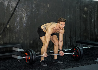 Caucasian Shirtless Tattooed Man Exercising Using Straight Bar Back Rows