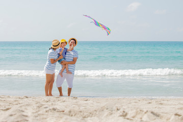 Happy asian family enjoy with kine on the beach