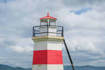 Old white lighthouse with red stripe. Entrance to Crinan channel. Crinan, Scotland.