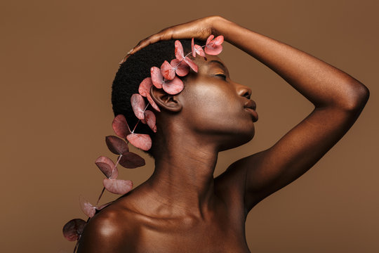 Beauty portrait of young half-naked african woman holding exotic flower