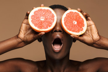 Beauty portrait of young half-naked african woman holding grapefruit