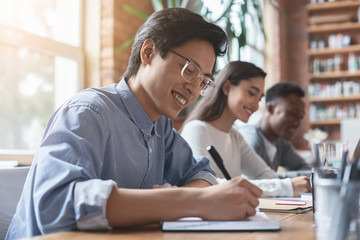 Young asian guy taking notes, having business meeting with colleagues