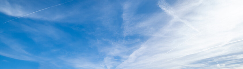 White fluffy cirrus and cirrocumulus clouds in deep blue azure sky and sunlight glow in sky