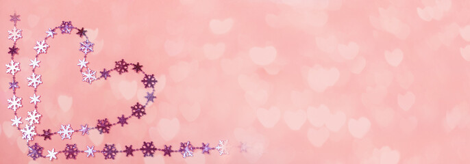 Creative Valentine's day banner. Heart of shiny lilac snowflakes on gentle pink background with bokeh in hearts shape. 