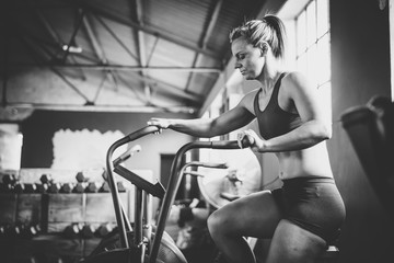 Fototapeta na wymiar Female fitness model exercising on an elliptical training bike in a gym