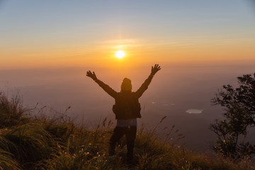 Fototapeta premium rear of happy woman stand on top mountain looking view with sunrise and mist at (Doi Norg Doi Luang National Park) Phayao province. soft focus.