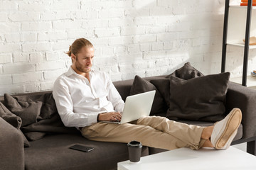 Photo of handsome businessman working on laptop computer in apartment
