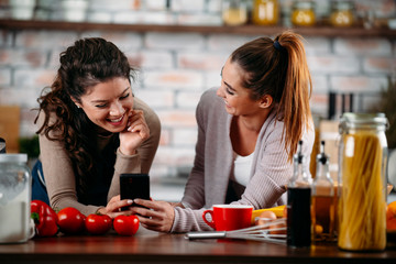 Sisters cooking together. Two friends having fun in kitchen. 
