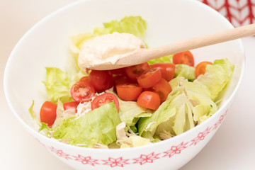 Cooking Salad. Female hands add the sauce to Caesar.