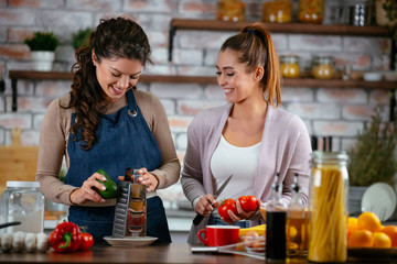 Two friends having fun in kitchen. Sisters cooking together. 