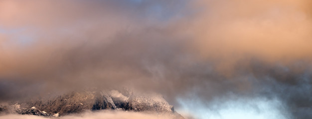 Fluffy clouds in evening twillight overcast sky view. Mountain tops silhouettes in clouds.