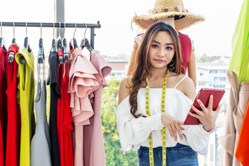 Woman fashion designer working in clothing shop studio and using tablet computer in the studio. Tailor sewing. People lifestyle concept .