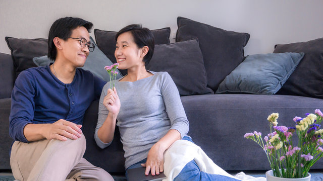 Young asian couple hugging in love at front of sofa in home on valentines day and copy space, use for couple in love content.