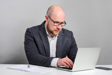 A man works with a laptop.  Manager is sitting at the table. 