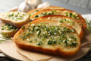 Toasted garlic bread on circle wooden board, close up