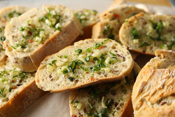 Toasted garlic bread slices on baking paper, close up