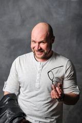 man holds glasses in his hands. Man with glasses in hands smiling. The teacher slyly looks at the camera.