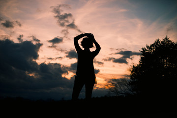 Silhouette of young woman against pink sky 