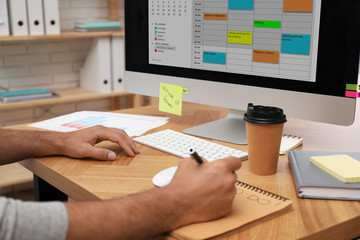 Man planning his schedule with calendar app on computer in office, closeup