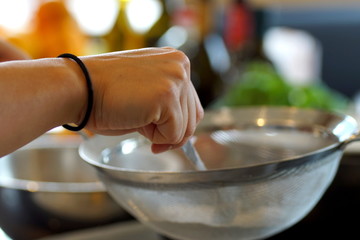 Passing powdered sugar through a colander