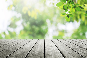 Wooden table and blurred green leaves in garden nature background.