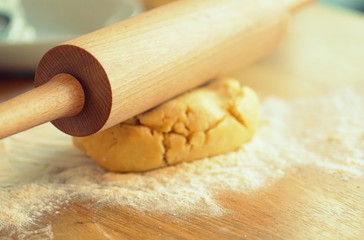 Close up of a rolling pin on a piece of dough in the kitchen.