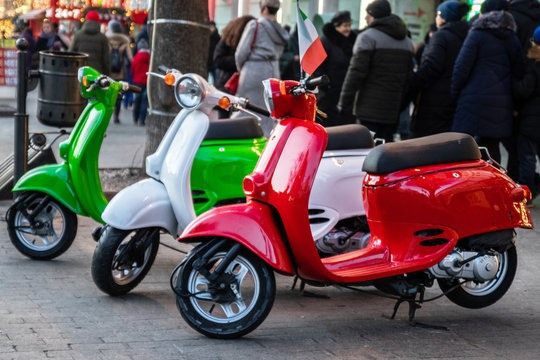 Three beautiful colored mopeds are parked on the street. Vehicle in the city