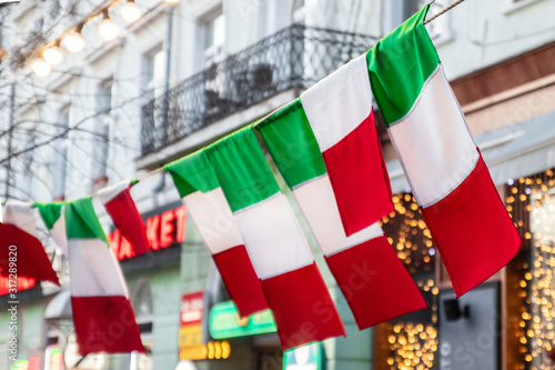 Flag of Italy hang on a city street. Tri-color flag fabric