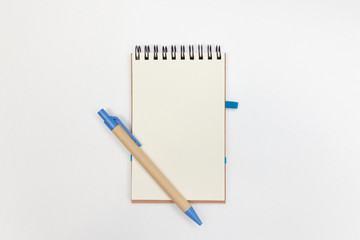 Eco notebook with recycled pen on a white background with copy space. Environmental friendly office elements.