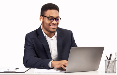 Happy black businessman in glasses listening to music