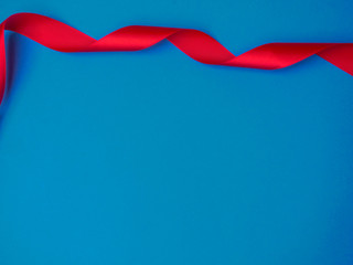 Satin red ribbon on trendy classic blue background. Ready for your design. Can be used for greeting card, holidays, gifts