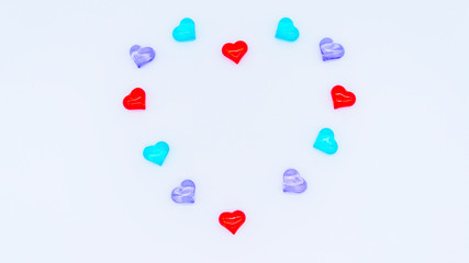 Valentine's Day holiday celebration concept. Red, blue and lilac glass hearts laid out in the shape of a heart on a white background. Copyspace.A big heart is made up of little hearts.