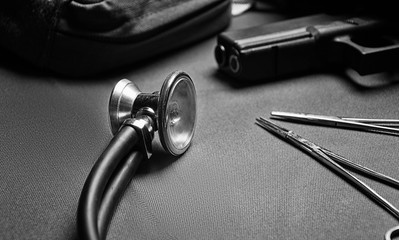 First aid kit, phonendoscope, set of scissors with a gun lie on a green background. View to the top...