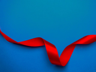 red silk ribbon twisted on a trendy classic blue background, festive postcard, copy space