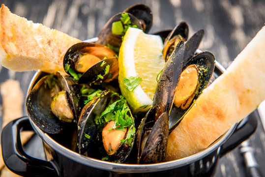Mussels in metal cooking dish and French Baguette with herbs