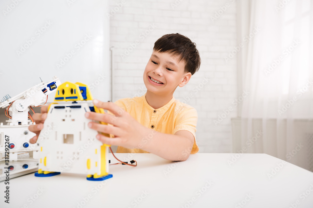 Poster happy schoolboy creating robot at lab, free space
