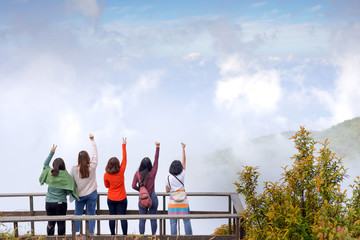 woman friendship team hike to top of mountain on new year long holiday and show finger symbol for...