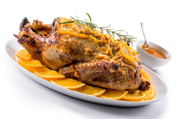 Orange duck on a plate and bowl with sauce