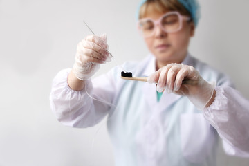 woman takes a sample from a toothbrush for genetic research in the laboratory, concept of DNA analysis, contamination with pathogens, establishing paternity