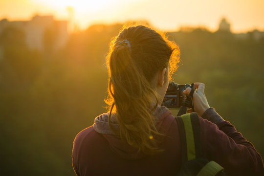 Silhouette of a girl taking pictures of sunrise