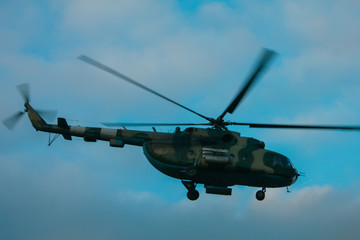 Fototapeta na wymiar Helicopter in flight at sunset above war field