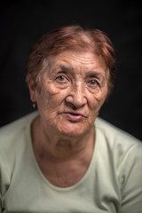 Portrait of an old woman against a dark background. Photographed close-up.